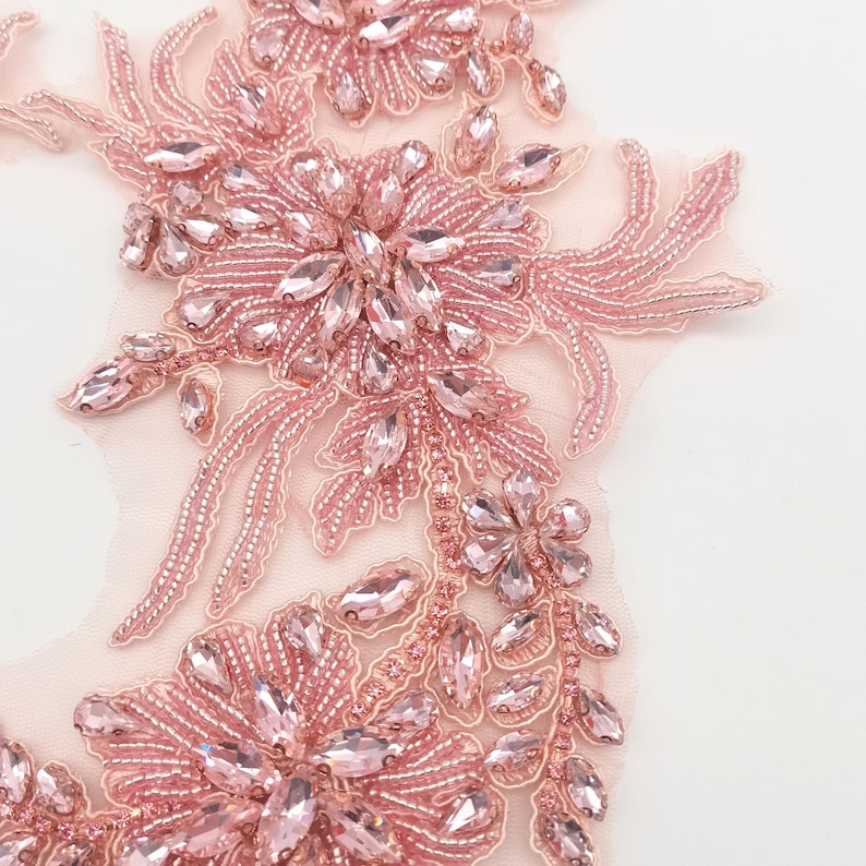 K&ouml;nnte beinhalten: Eine zarte rosa Perlenapplikation mit floralem Design und Kristallverzierungen. Die Applikation ist perfekt, um Kleidung, Accessoires oder Wohnaccessoires einen Hauch von Eleganz zu verleihen.