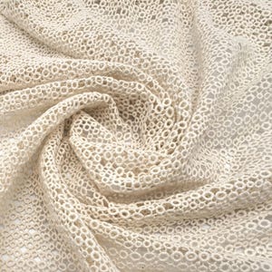May include: Cream-colored crocheted fabric with a delicate, circular pattern. The fabric is soft and lightweight, making it ideal for a variety of crafting projects.