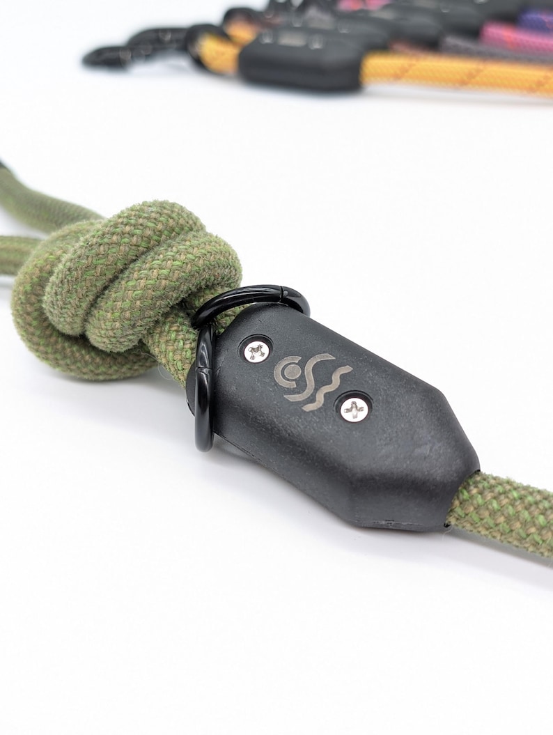 May include: Close-up of a green rope dog leash with a black plastic clasp. The clasp has a silver logo with a wave design and the text "CCS".