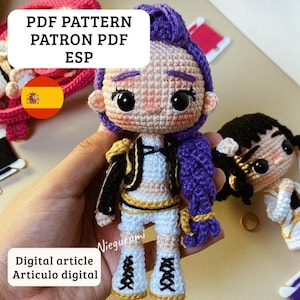 Puede incluir: Muñeca de ganchillo hecha a mano con un atuendo morado y negro, pantalones cortos blancos y zapatos blancos. La muñeca tiene un tono de piel claro, ojos negros y cabello morado. El texto en la imagen dice "PDF PATTERN PATRON PDF ESP" y "Digital article Articulo digital."