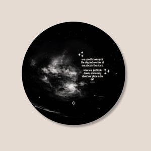 Puede incluir: Un diseño circular en blanco y negro que presenta una nebulosa y estrellas. La imagen incluye el texto: "we used to look up at the sky and wonder at our place in the stars. now we just look down, and worry about our place in the dirt."