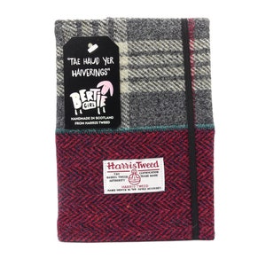 May include: A red, gray, and white plaid notebook with a black elastic closure. The notebook is covered in Harris Tweed fabric and has a tag that reads "TAE HAUD YER HAIVERINGS" and a small sheep illustration. The Harris Tweed label is visible on the bottom of the notebook.