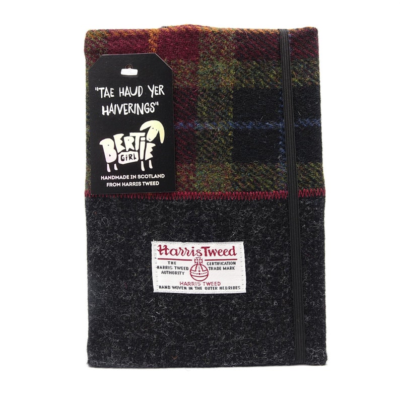 May include: A black and gray tweed notebook with a red, green, and blue plaid cover. The notebook has a black elastic closure and a label that reads "Harris Tweed" and "Hand Woven in the Outer Hebrides". The notebook also has a smaller label that reads "Tae Haud Yer Haiverings" and features a cartoon sheep.