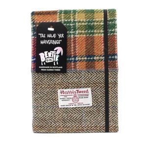 May include: A brown and green plaid notebook with a black elastic closure. The notebook is made from Harris Tweed and has a label that says "Tae Haud Yer Haiverings" and "Bertie Girl". The label also says "Handmade in Scotland from Harris Tweed".