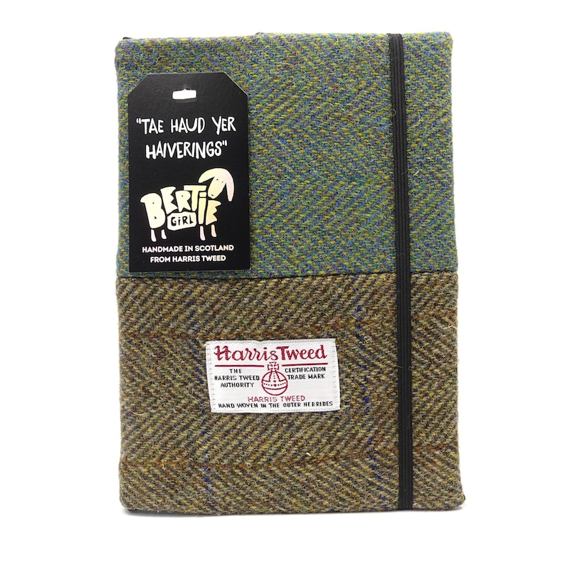 May include: A green and brown tweed notebook with a black elastic closure. The notebook has a tag that says "Tae Haud Yer Haiverings" and a sheep illustration with the text "Bertie Girl Handmade in Scotland from Harris Tweed". The notebook also has a label that says "Harris Tweed" with the Harris Tweed Orb logo and the text "The Harris Tweed Authority Certification Trade Mark Harris Tweed Hand Woven in the Outer Hebrides".