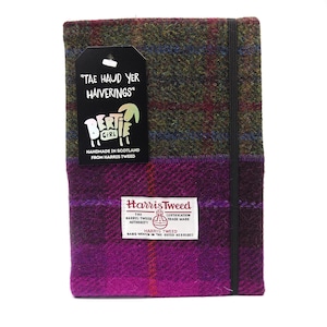 May include: A purple and green plaid notebook cover with a black elastic closure. The cover is made from Harris Tweed and has a label that reads "Harris Tweed, The Harris Tweed Authority, Certification Trade Mark, Hand Woven in the Outer Hebrides". The cover also has a tag that reads "Tae Haud Yer Haiverings" and a logo that says "Bertie Girl, Handmade in Scotland from Harris Tweed."
