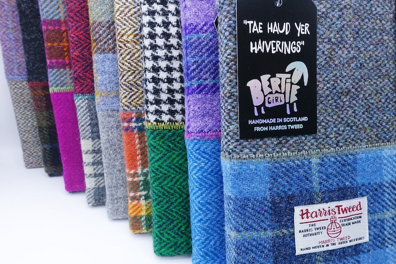 May include: A row of colorful patchwork fabric pouches with a tag that reads "Tae Haud Yer Haiverings" and a logo of a sheep with the text "Bertie Girl" and "Handmade in Scotland from Harris Tweed". The pouches are made from Harris Tweed and have a label that reads "Harris Tweed" with the Harris Tweed Orb logo.