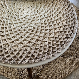 May include: A round crocheted table runner with a gradient of beige and brown colors. The runner is made with a delicate stitch pattern and has a scalloped edge.