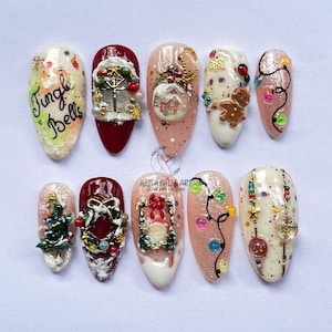 Puede incluir: Un conjunto de diez diseños de uñas con temática navideña. Cada uña presenta decoraciones festivas únicas, que incluyen figuras en miniatura de Papá Noel, hombres de jengibre, árboles de Navidad y el texto "Jingle Bells". Las uñas están pintadas en varios colores, incluyendo rojo, blanco y dorado.