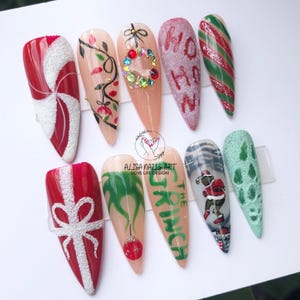 May include: Set of ten Christmas-themed nail art designs. The designs include a candy cane, a present, a wreath, a Christmas tree, a Grinch, a Santa Claus, and a snowflake. The nails are painted in various colours, including red, green, white, and gold.