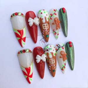 May include: Set of ten Christmas-themed nail art designs. The designs include candy canes, gingerbread houses, gingerbread men, and Christmas lights. The nails are painted in red, white, and green.