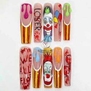 May include: Set of ten long, pink, white, and yellow acrylic nails with a red and yellow striped design. The nails are decorated with a clown face, red dripping paint, and the words "Loser" and "We All Float Down Here".