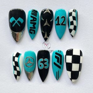 May include: A set of ten artificial nails with a racing theme. The nails feature designs in black, teal, and silver, including racing flags, the AMG logo, the number 12, a checkered flag pattern, the Mercedes logo, the number 63, and the F1 logo.