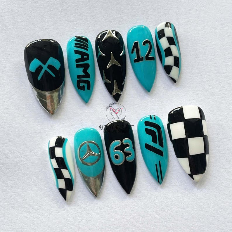 May include: A set of ten almond-shaped artificial nails. The nails feature designs in black, teal, silver, and white, including racing-themed graphics, numbers, and checkered patterns. The nails are arranged on a white surface.