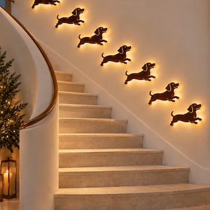 May include: A series of seven black dog-shaped wall silhouettes arranged in a diagonal line along a staircase wall. Each silhouette features a warm, glowing LED backlight that creates a soft halo effect against the wall surface.