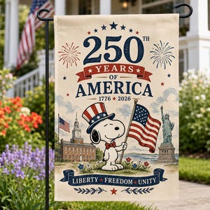 Może przedstawiać: Beżowa flaga ogrodowa upamiętniająca 250 lat Ameryki, z Snoopy'm w patriotycznym kapeluszu trzymającym flagę USA. Flaga zawiera napis "250th Years of America 1776-2026" z ilustracjami Dzwonu Wolności i Statuy Wolności.