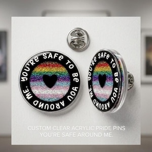 Puede incluir: Alfileres de orgullo de acrílico transparente con un diseño de arcoíris y un corazón negro. Los alfileres tienen el texto "You're safe to be around me". Los alfileres son redondos y tienen un respaldo plateado.