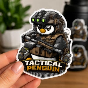 以下が含まれることがあります： タクティカルな軍用装備を身にまとったペンギンのキャラクターのダイカットステッカー。ナイトビジョンゴーグル付きのヘルメットとベストを着用し、ライフルを構えている。ペンギンの下にある黒いバナーには「TACTICAL PENGUIN」という文字が記されている。