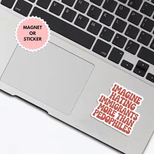 May include: A laptop with two stickers. One sticker is pink with the text "MAGNET OR STICKER". The other sticker has the text "IMAGINE HATING IMMIGRANTS MORE THAN PEDOPHILES" in red letters.