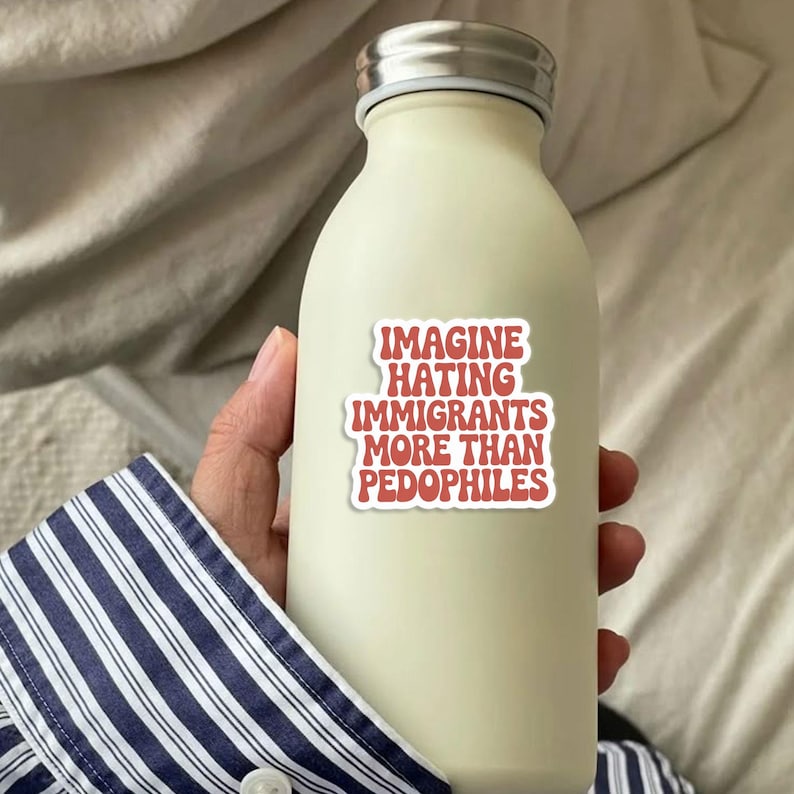 May include: A cream-colored water bottle with a silver lid. A sticker on the bottle reads "IMAGINE HATING IMMIGRANTS MORE THAN PEDOPHILES" in red text. The bottle is held by a person wearing a blue and white striped shirt.