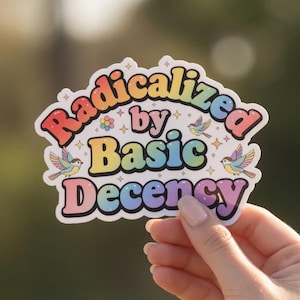 Könnte beinhalten: Ein farbenfroher Aufkleber mit dem Text "Radicalized by Basic Decency" in einer Regenbogen-Schriftart. Der Aufkleber zeigt kleine Vogelillustrationen und Sternakzente mit einem weißen Rand.