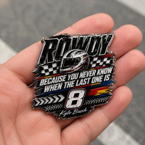 May include: A rectangular metal pin with the word "ROWDY" in bold, distressed lettering. The pin features a racing helmet graphic, the number "8", and the text "BECAUSE YOU NEVER KNOW WHEN THE LAST ONE IS". The name "Kyle Busch" is also included.