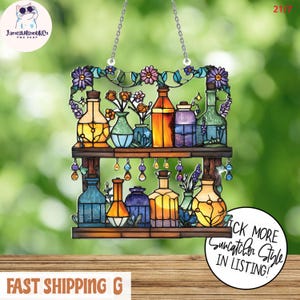 May include: Stained glass suncatcher featuring two wooden shelves with colorful bottles and vases. The top shelf has flowers and the text "JamesWilsonUKC PNG SHOP". The bottom shelf has more bottles. The suncatcher hangs from a chain.