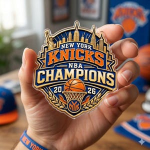 May include: A clear acrylic ornament featuring a New York Knicks NBA Champions graphic with the Statue of Liberty, city skyline, a basketball, and the text New York Knicks NBA Champions 20 26. The design uses blue, orange, and gold colours.
