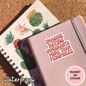 May include: A pink notebook with a sticker that reads "IMAGINE HATING IMMIGRANTS MORE THAN PEDOPHILES." A botanical illustration notebook is visible in the background. The word "waterproof" is written on the bottom left.