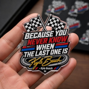 May include: A clear, rectangular pin with a racing theme. It features two checkered flags and the text "BECAUSE YOU NEVER KNOW WHEN THE LAST ONE IS" in white, red, and blue. The pin also includes the name "Kyle Busch" in gold.