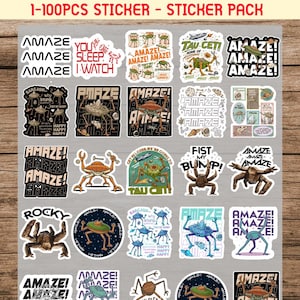 Puede incluir: Un paquete de pegatinas con varios diseños, incluyendo la palabra "AMAZE" e ilustraciones temáticas de extraterrestres. Algunas pegatinas incluyen frases como "You Sleep I Watch" y "Fist My Bump!". Las pegatinas son coloridas y de estilo caricaturesco.