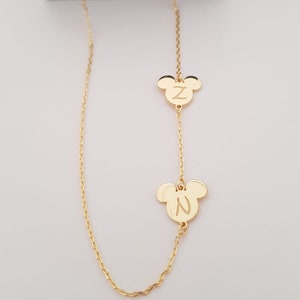 May include: A gold chain necklace with two Mickey Mouse head charms. The charms have the letters "Z" and "N" engraved on them.