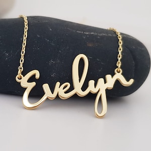 May include: Gold necklace with the name "Evelyn" written in a cursive script.