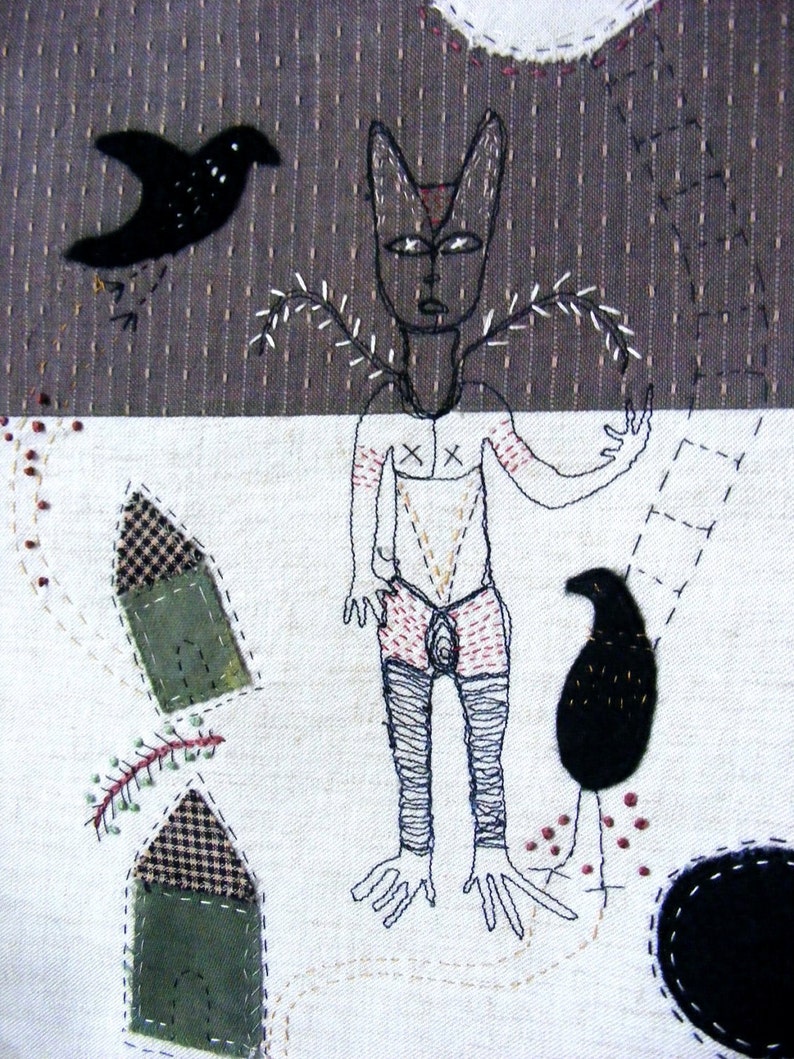 May include: A black and white embroidered artwork depicting a stylized human figure with a bird and other abstract shapes. The figure has a cross on its chest and is wearing a skirt. The background is a textured fabric.