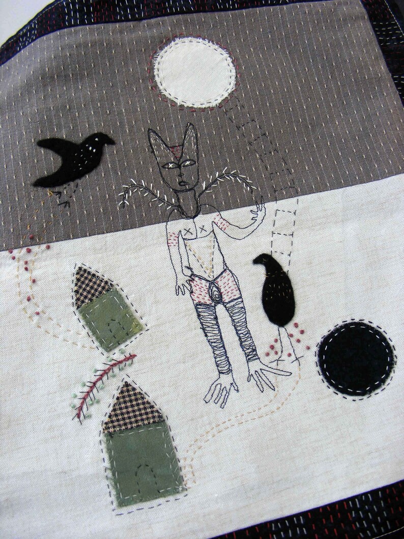 May include: A white fabric background with black and white embroidered figures. A black bird with a long tail is flying above a figure with a long neck and long legs. The figure has a white body with black lines and a black circle on its chest. The figure is standing next to a ladder with a black bird on the top rung. There are two small houses with black and white checkered roofs and green walls. The background is a dark gray fabric with a white circle in the upper left corner.