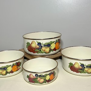 May include: A white ceramic mug with a black handle and the text "But First, Coffee" in a bold, black font. The mug is set against a blurred background, suggesting a cozy setting.