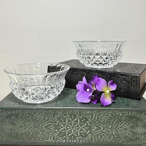 May include: Two clear glass bowls featuring a diamond-cut pattern on the lower exterior and smooth, vertical fluting along the upper rim. The bowls are transparent with a reflective surface, showcasing a geometric texture and a wide, open top design.