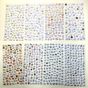May include: Sheets of colourful stickers featuring various cute designs. The stickers include food items, animals, and other whimsical shapes in shades of brown, pink, blue, and white. The stickers are arranged on clear, rectangular sheets.