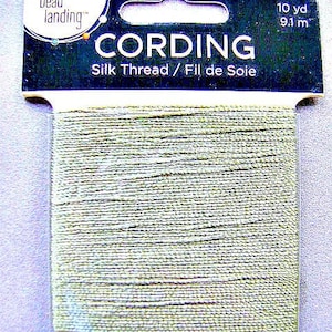 May include: A spool of green silk cording thread labelled "CORDING Silk Thread / Fil de Soie" with the brand name "bead landing" and the length "10 yd 9.1 m".