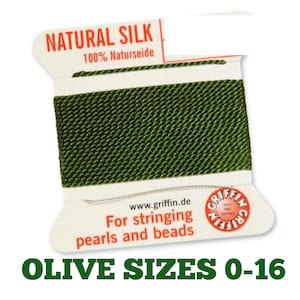 Op de afbeelding: Een spoel olijfgroen natuurlijk zijden koord voor het rijgen van parels en kralen. De witte kartonnen verpakking bevat de tekst NATURAL SILK, 100% Naturseide, www.griffin.de, For stringing pearls and beads en een rood Griffin-logo.