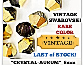 May include: A collection of 8mm faceted beads with a dual-tone finish, featuring one half clear crystal and one half 24k gold metallic coating. The image includes text stating VINTAGE SWARVSKI RARE COLOR VINTAGE LAST OF STOCK CRYSTAL-AURUM.