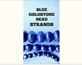 May include: Blue goldstone bead strands. The beads are round and have a speckled appearance. There are three strands of beads, each with a different size bead.