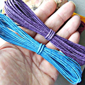 Puede incluir: Dos paquetes de cordel de m&uacute;ltiples hebras, uno en azul vibrante y otro en morado intenso. Cada paquete est&aacute; cuidadosamente enrollado y asegurado con un peque&ntilde;o lazo de cordel a juego. La textura del cordel parece fibrosa y mate, con un grosor constante.