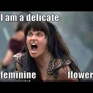 May include: A woman with dark hair and a fierce expression shouts "I am a delicate feminine flower".