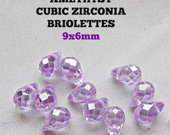 May include: A collection of light purple, faceted briolette-shaped cubic zirconia beads. The text AMETHYST CUBIC ZIRCONIA BRIOLETTES 9x6mm is printed above the beads. These translucent, teardrop-shaped stones feature a geometric cut.