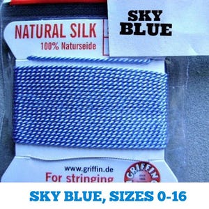 May include: A spool of sky blue natural silk thread for stringing. The label reads "NATURAL SILK 100% Naturseide" and "SKY BLUE". The label also includes the website "www.griffin.de" and the text "For stringing".