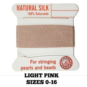 May include: A spool of light pink natural silk thread, labeled "NATURAL SILK" and "100% Naturseide." The label also states "For stringing pearls and beads" and "SIZES 0-16."