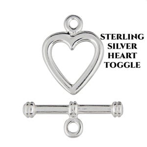 May include: Sterling silver heart toggle clasp. The clasp is made of silver and has a heart-shaped design. The toggle is a bar with a ring on one end and a round knob on the other.