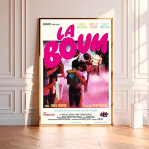 Może przedstawiać: Winietkowy plakat filmu francuskiego "La Boum" przedstawiający grupę nastolatków tańczących w dyskotece. Plakat jest w kolorze różowym, białym i czarnym, z tytułem "La Boum" w dużych różowych literach.