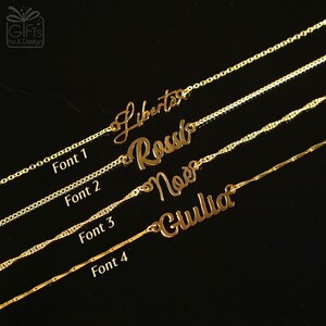 May include: Gold-colored name necklaces with different fonts. The names "Liberta", "Rossi", "Noe", and "Giulia" are displayed. The image also shows the text "Font 1", "Font 2", "Font 3", and "Font 4".